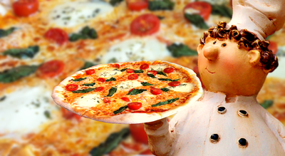 Chef holding pizza in front of a pizza close-up background
