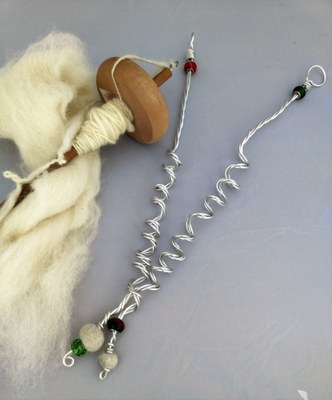 a drop spindle with white yarn wrapped around it